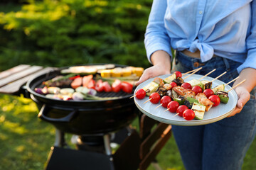 Woman with delicious grilled vegetables near barbecue grill outdoors, closeup. Space for text