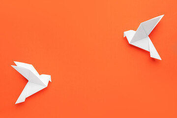 Beautiful white origami birds on orange background, flat lay. Space for text