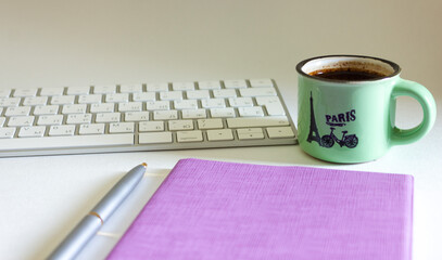 Cup of coffee with keyboard and notepad with pen