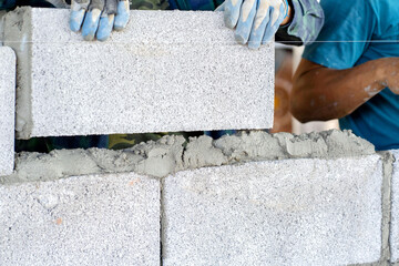 masonry worker make concrete wall by cement block and plaster at construction site