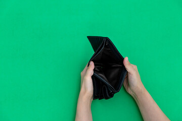 Woman hand open an empty wallet on green background