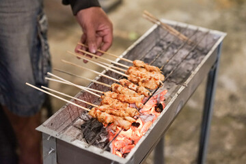 Sate ayam or chicken satay with charcoal ingredient on red fire charcoal grilling, cooking satay.