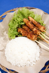 Red chicken satay legend with rice and vegetable salad. Sate Ayam. Traditional meat chicken satay in a plate ready to eat. Dinner dish indonesian cuisine.