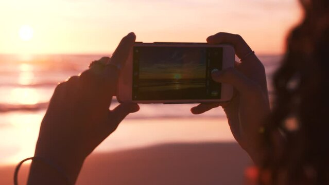 Hands, phone and woman at the beach at sunset for travel, photography and freedom in nature, relax and zen. Hand, girl and photographer travelling for pictures at the sea for summer holiday in Cancun