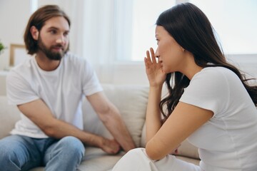 An Asian woman is sad and crying with her male friend at home. Stress and misunderstanding in a relationship between two people and supporting each other's mental and emotional well-being