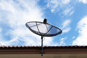 Satellite dish television black net with blue sky white clouds like cotton wool communication technology network on roof of house. Suitable for receiving signal from satellite that float in space.