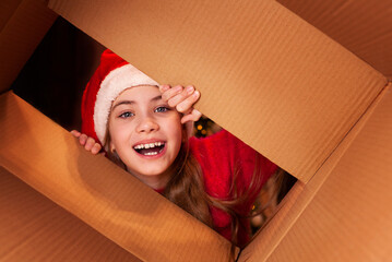 a child in a santa hat opens a large cardboard box