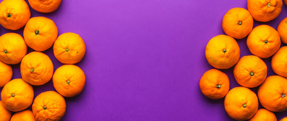 Ripe bright orange tangerines on lilac background, fruit banner. Top view with copy space