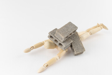 デッサン人形と玩具のコンクリートブロック。重荷のイメージ