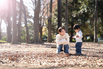 公園で遊ぶ母と子のポートレート　何故か棒が好きな男児 広角