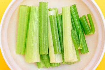 Fresh Chopped Celery Sticks with Water Drops in White Bowl - Top View. Vegan and Vegetarian...