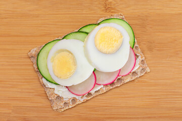 Whole Grain Crispbread with Fresh Cucumber, Egg, Cream Cheese and Radish on Bamboo Cutting Board. Easy Breakfast. Quick and Healthy Sandwiches. Crispbread with Tasty Filling. Healthy Dietary Snack
