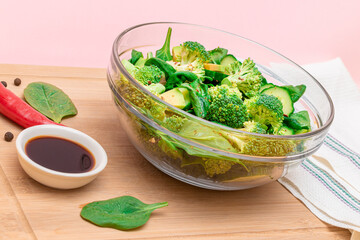 Fresh Green Salad of Avocado, Broccoli, Spinach and Cucumber with Soy Sauce and Red Hot Pepper on Wooden Cutting Board. Vegan Salad. Vegetarian Culture. Raw Food. Healthy Eating and Vegetable Diet