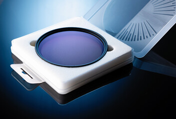 neutral gray lens filter on black glass in protective case, blue backlight