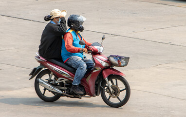 Fototapeta na wymiar A taxi driver on a motorcycle rides with a woman. The moto-taxi carry a passenger
