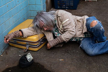 Selective focus Addiction aged man sitting on dirty street with old blanket excited with money donation, unemployed homeless get cold need help for medical care, abandoned poverty begging for money.