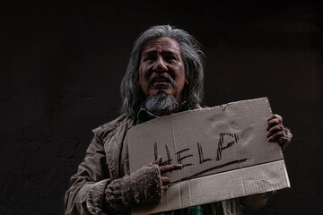 Homeless poverty man holding signs for help against wall. old pity man with beard begging for...