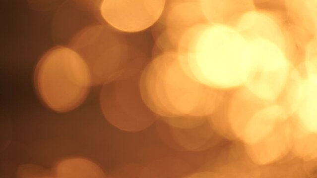 Blurred golden sea at sunset. The sun reflects and sparkles on the waves with bokeh, illuminating the golden sea. Holiday recreation concept. Abstract nautical summer ocean sunset nature background