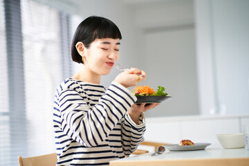 家のダイニングで食事をする女性 