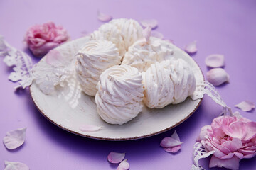 Obraz na płótnie Canvas Natural homemade vanilla no sugar marshmallows on purple background. Healthy sweets, natural food. Romantic tea rose decorations. Valentines day present