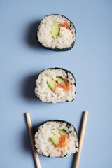 Three sushi and chopsticks on a blue background