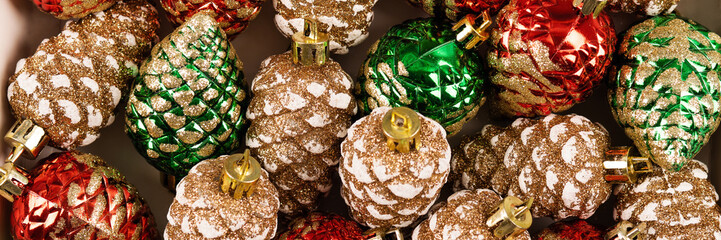 Abstract background of Christmas decorations in the form of pine cones in green, red and gold...