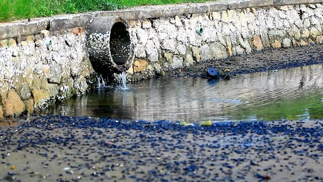 Dirty water flows from the pipe into the river, environmental pollution. industrial waste