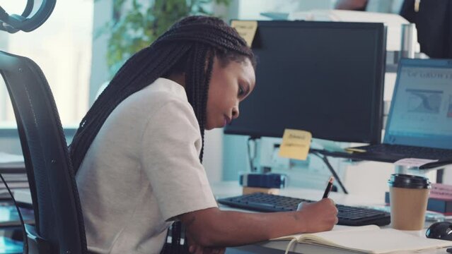 Writing, business woman and marketing employee working on a office schedule in a notebook. Black woman, web worker and sales planning on paper doing company research for a computer strategy project
