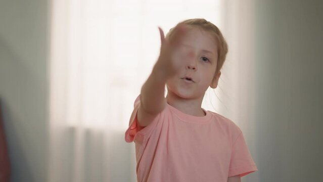 Little blonde girl shoots for finger imitating gun in room