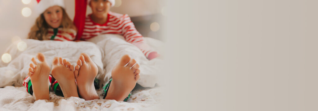 Baby feet peek out from under the blanket. Two children of different ages. Feet close up. Concept of christmas and new year