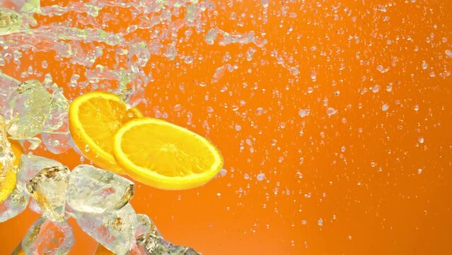 Cold orange slices, ice cube and liquid, orange background in super slow motion 1000fps.Fresh orange fruit, ice cube and drops juicy or alcohol beverage or energy drink or shake soda pop splash pours
