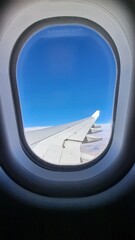 View from the window of the airplane. Rear of the wing. Blue sky. White clouds in the background out of focus. Selective focus. Copy space