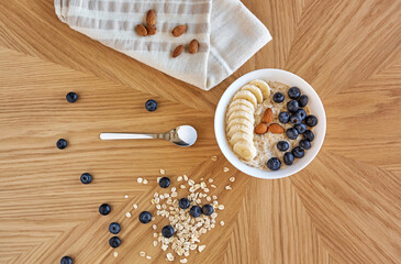 Oatmeal bowl with banana, almonds and blueberries on wooden table. Healthy breakfast. Top view