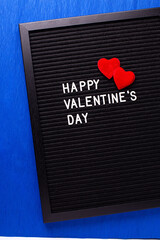 St. Valentines day postcard. Letterboard with congratulation phrase  andtwo red hearts oh bright blue paper textured background. Top view. Bokeh light. - 554425687