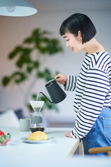 部屋でコーヒーを淹れる若い女性