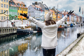 A happy tourist woman enjoys the view to the beautiful Nyhavn area in Copenhagen, Denmark, during...