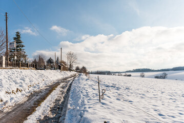 country track in winter with snow and beautiful blue clouded sunny sky