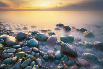 Sunset on the sea stones shore.