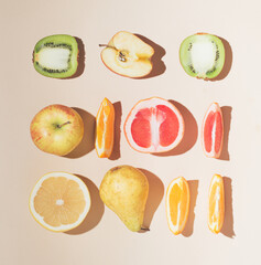 Creatively arranged fresh summer fruit on sandy colored background. Minimal flat lay