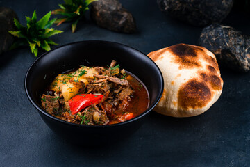 Hot stewed beef with potatoes, sweet peppers, onions in tomato sauce with herbs and flatbread.