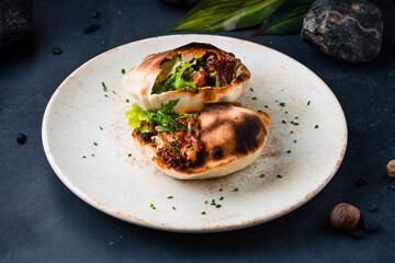 Pita with sweet and sour fried chicken, arugula, lettuce and greens on a plate.