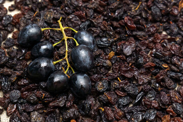 Black raisins with grapes on a wooden background, healthy snack, dietary product.