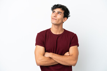 Young Argentinian man isolated on white background looking up while smiling