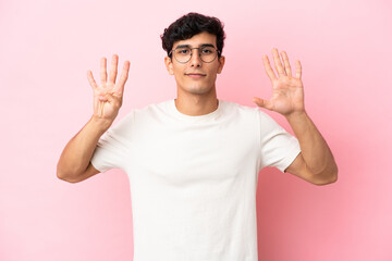 Young Argentinian man isolated on pink background counting nine with fingers