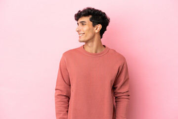 Young Argentinian man isolated on pink background looking side