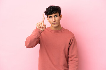 Young Argentinian man isolated on pink background counting one with serious expression