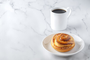 Swedish concept of balanced lifestyle-Lagom. Cozy morning, minimalism composition with cup of coffee, homemade bun on a white stone background with copy space. Close up.