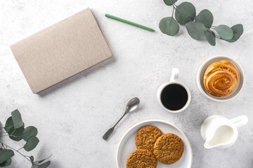 Scandinavian Lagom style concept-not too little, not too much. Cozy morning, with cup of coffee, milkman, bun, vegan cookies, notebook on the grey background. Top view, flat lay, copy space.