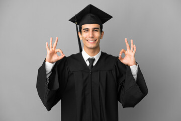 Young Argentinian university graduate isolated on grey background showing an ok sign with fingers