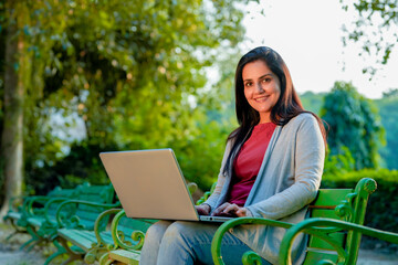 Young Indian woman using laptop at park